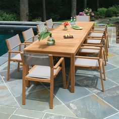 an outdoor dining table with six chairs next to a swimming pool and stone patio area