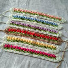 four crocheted pieces of yarn with different colors and sizes on them, all lined up in rows