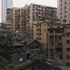 an urban area with tall buildings and trees in the foreground, on a cloudy day