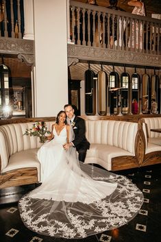 a bride and groom posing for a photo in front of a white couch at their wedding reception