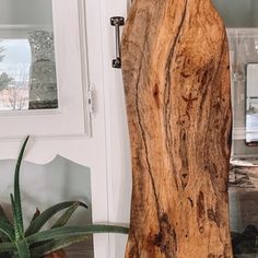 a wooden surfboard sitting next to a potted plant