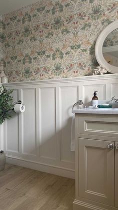 a white sink sitting under a bathroom mirror next to a wooden floor and wall mounted faucet