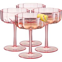 four wine glasses with lemons in them sitting next to each other