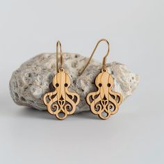 wooden earrings with an intricate design on them sitting on a rock next to some rocks