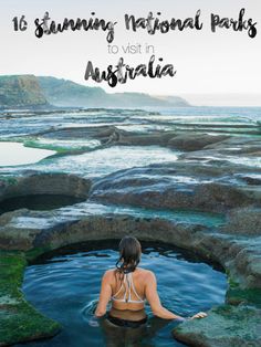 a woman is sitting in the water near rocks