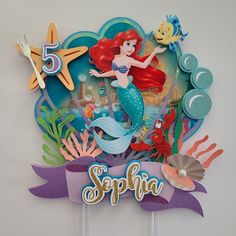 there is a cake topper with an image of ariel the little mermaid on it