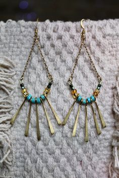 Hanging flat cable chain beaded arch with brass fringe detail. Bohemian Gold Earrings With Beaded Chain, Bohemian Turquoise Beaded Earrings With Brass, Bohemian Turquoise Beaded Earrings In Brass, Bohemian Turquoise Beaded Brass Earrings, Bohemian Turquoise Beaded Earrings, Metal Tassel Earrings With Dangling Beads, Turquoise Metal Jewelry With Dangling Beads, Turquoise Tassel Earrings With Dangling Beads, Turquoise Beaded Brass Jewelry