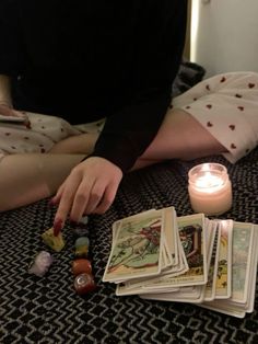 a woman is sitting on the floor next to some cards and a candle with candles in it