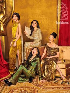 three women in gold and green dresses posing for the camera with one holding a fan