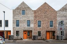 a car is parked in front of three brick buildings with orange doors on the street