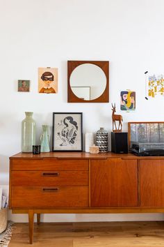 a wooden dresser with pictures on the wall