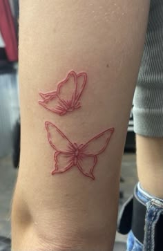 a tattoo with two butterflies on the side of her leg, one is red and the other is pink