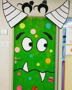 a door decorated with an angry green monster's face and two black cats sitting on top of it