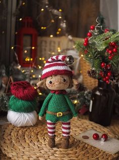 a crocheted elf doll sitting on top of a basket next to christmas decorations