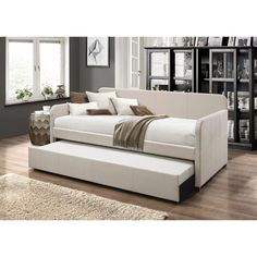 a white couch sitting on top of a hard wood floor next to a book shelf