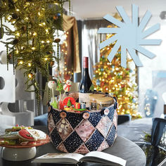 an open book sitting on top of a table next to a wine bottle and christmas tree