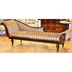 a striped couch sitting on top of a wooden floor next to a chest of drawers