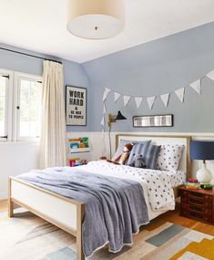 a bedroom decorated in blue and white with bunting flags on the wall above the bed