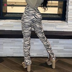 a woman standing in front of a window wearing zebra print pants