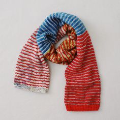 two knitted scarves sitting next to each other on top of a white surface