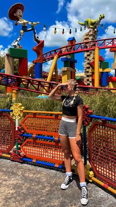 a woman standing in front of a roller coaster