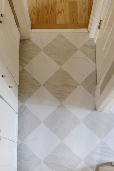 an empty bathroom with white cabinets and checkered tile on the floor is seen from above