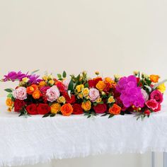 colorful flowers are arranged on a white table