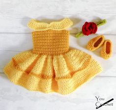 a crocheted baby dress and booties with a rose