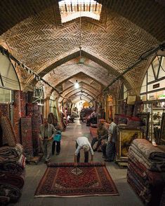 people looking at rugs on the floor in an old building with brick walls and arched ceilings