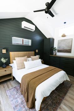 a large bed sitting under a ceiling fan in a bedroom next to a wooden dresser