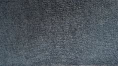 a close up view of the back of a blue denim fabric textured with white stitching