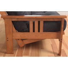 a wooden bed frame sitting on top of a hard wood floor next to a black pillow