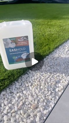 a bottle of eaod sitting on top of a grass covered ground next to a walkway