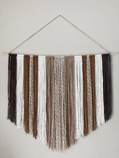 the wall hanging is decorated with different colored fringes and wood strips, which are hung on