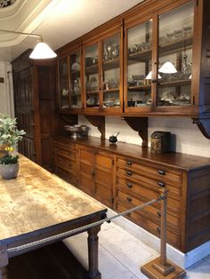 an old fashioned kitchen with wood cabinets and marble counter tops, along with a wooden dining room table