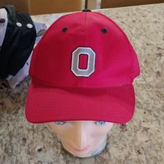 a red hat with the letter o on it sits next to a mannequin's head