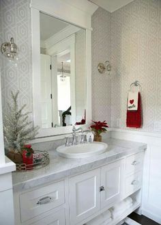 a bathroom with a sink, mirror and christmas decorations on the counter top in front of it