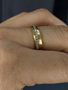 a woman's hand with a gold wedding band and diamond set in the middle