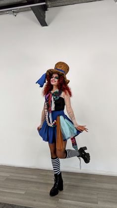 a woman dressed up as a mad hatter posing for the camera in front of a white wall