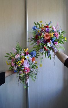 two people holding flowers in front of each other with their hands on the flower bouquets