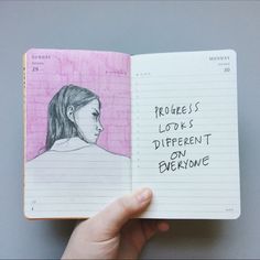 a hand holding an open notebook with a drawing of a woman's face on it