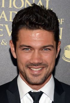 a close up of a person wearing a suit and tie with a smile on his face