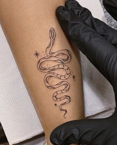 a person with a tattoo on their arm holding a black glove and gloves are next to a