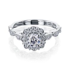 a white gold engagement ring with an intricate halo setting and round brilliant cut diamonds on the band