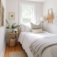 a white bed sitting next to a window and a wooden table with flowers on it