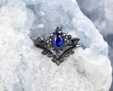 a blue ring sitting on top of a rock covered in ice and snow flakes