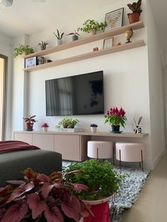 a flat screen tv mounted to a wall in a living room with potted plants