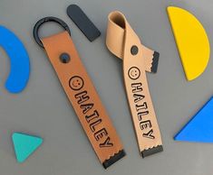 two leather keychains with the words whatever on them next to scissors and magnets