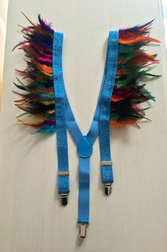 a blue strap with colorful feathers attached to it's ends on a white surface