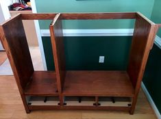 a wooden shelf sitting on top of a hard wood floor next to a green wall